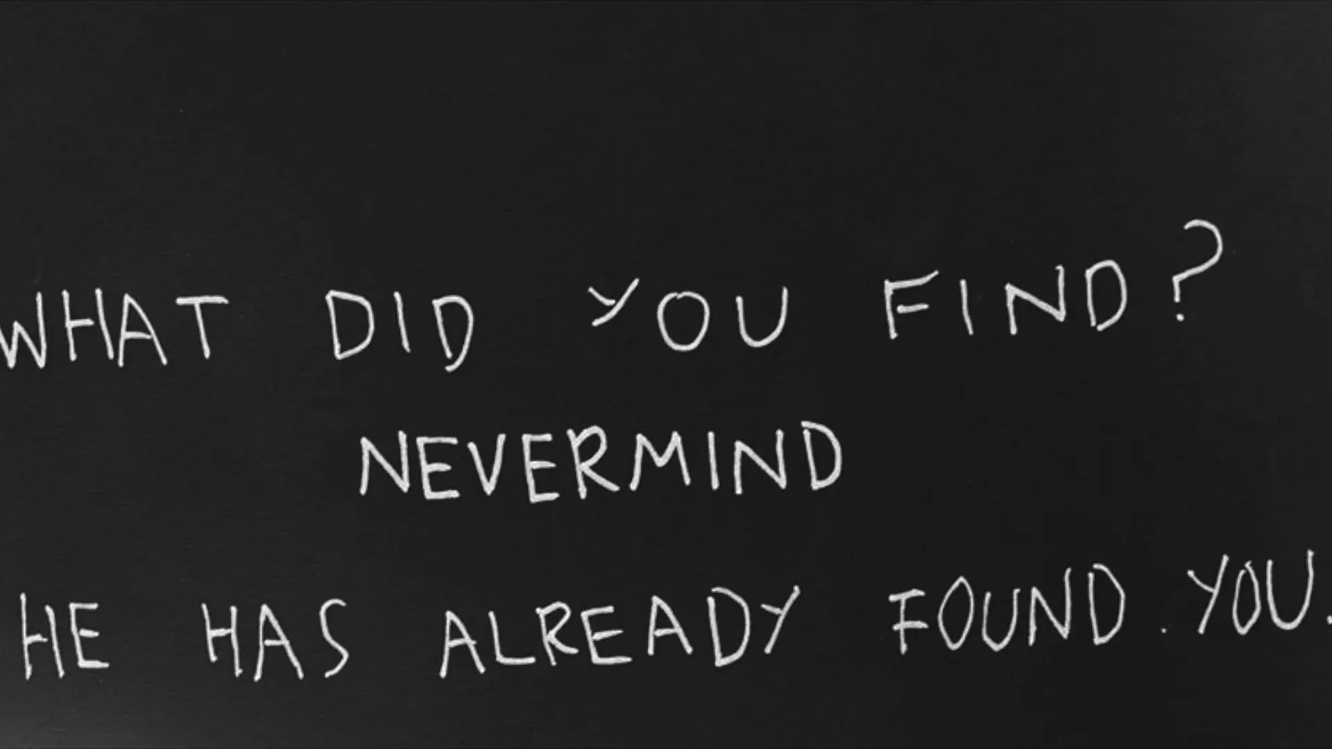 Hand-lettered chalk on a dark ground: WHAT DID YOU FIND? NEVERMIND. HE HAS ALREADY FOUND YOU.