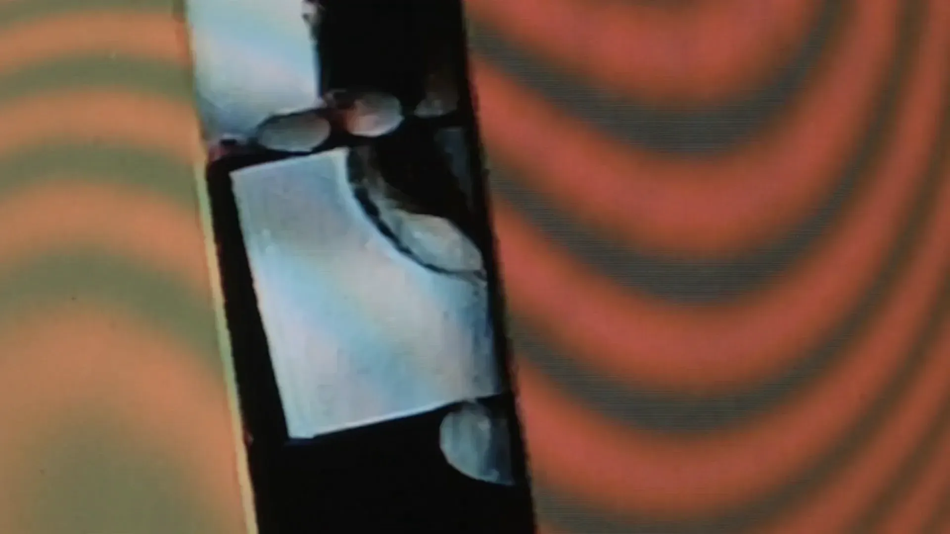 A screen filling the frame, showing concentric rings of orange and black pulsing out from a centre.